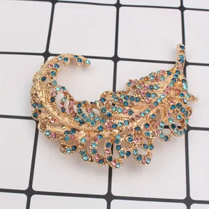 Detailed macro shot of an elegant golden feather brooch with blue and pink rhinestones