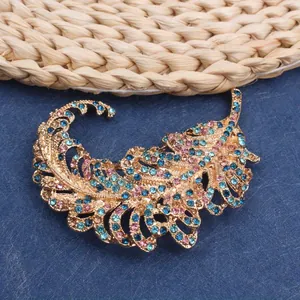 Macro detail of gold hollow feather brooch with sparkling blue and pink rhinestones
