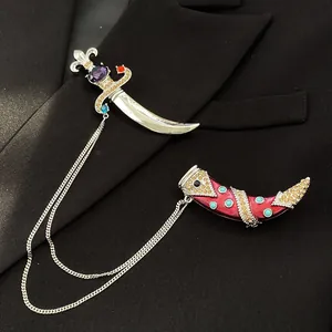 Vintage scimitar dagger brooch with colorful crystals shown on a black suit lapel