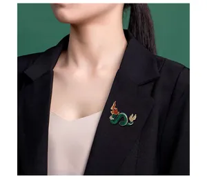 Close-up of vintage dragon brooch with green enamel and rhinestones on black blazer
