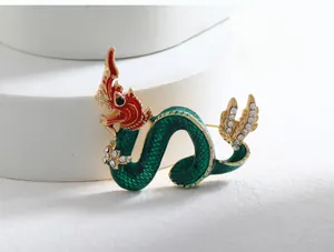 Close-up detail of a vintage Chinese dragon brooch with green enamel and rhinestones