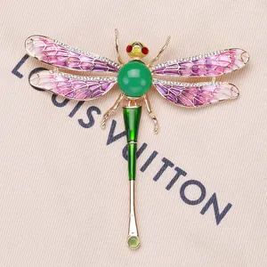 Detail view of an enamel dragonfly brooch with vibrant purple wings and green body