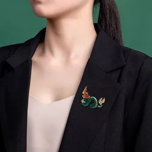 Vintage Chinese dragon brooch with green enamel and shiny rhinestones on a black blazer