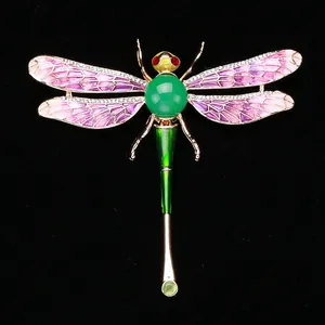 Detailed macro view of an enamel dragonfly brooch with purple wings and green bead
