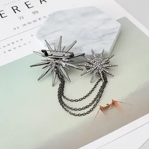 Detail of rhinestone starburst brooch with elegant tassel chains on marble