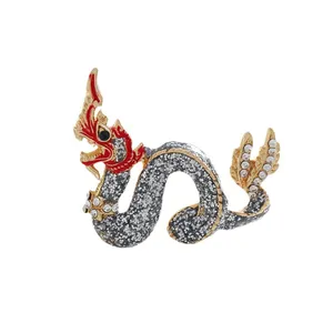 Vintage Chinese dragon brooch with red enamel and sparkling rhinestones on white background.