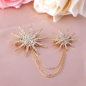Elegant gold starburst brooch with rhinestone tassels on a peach fabric background