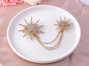 Detailed macro view of a golden snowflake brooch with flowing chains and set crystals.