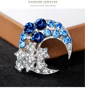 Gros plan d'une broche lune et étoile argentée avec des strass bleus très éclatants.
