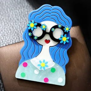 Vue détaillée d'une jolie broche en acrylique d'une fille aux cheveux bleus et lunettes.