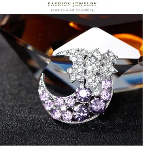 Vue détaillée d'une broche lune et étoile argentée avec strass violets et blancs.