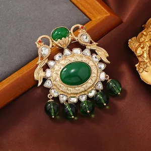 Detailed view of a vintage gold brooch with green stones and elegant peacock motifs