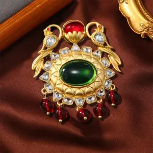 Detailed view of a vintage court style brooch with green oval stone and red bead drops
