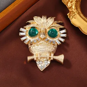 Close-up of vintage golden owl brooch with emerald green eyes and white rhinestones