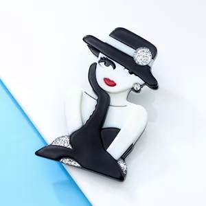 Close-up of elegant acrylic girl brooch in black and white with glitter accents.