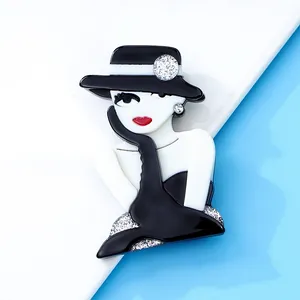 Close-up of stylish black and white acrylic girl brooch with silver glitter accents.