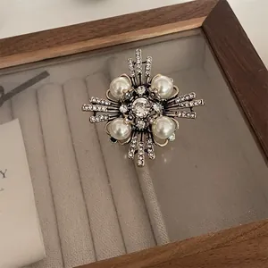 Close-up of a vintage cross brooch with elegant pearls and sparkling rhinestones.