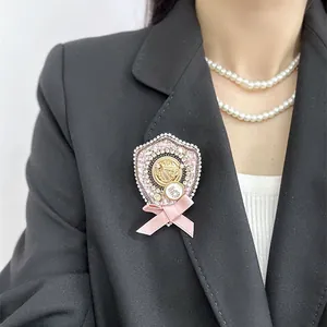Detail view of a vintage pink bow brooch with a number 5 charm on a black blazer.