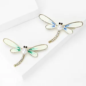 Detailed close-up of elegant dragonfly brooches featuring pearls and colorful enamel wings