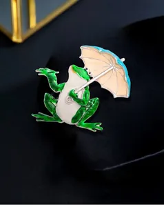 Macro view of an exquisite green enamel frog brooch holding a colorful umbrella