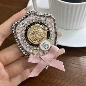 Retro pink tweed bow brooch with rhinestones and golden crown crest, measuring 7.5cm