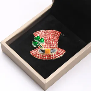 Detailansicht einer funkelnden roten Hut-Brosche mit Strass und grünem Kleeblatt