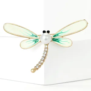Detailed view of an elegant dragonfly brooch with pearl and green enamel wings