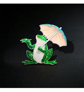 Close-up of a creative enamel frog brooch holding a colorful umbrella design detail
