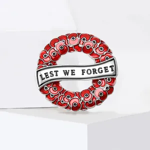 Detailed macro view of red enamel poppy wreath brooch featuring Lest We Forget banner