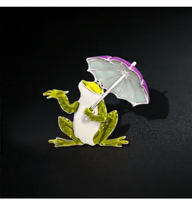 Close-up detail of a whimsical enamel frog brooch holding a vibrant purple umbrella