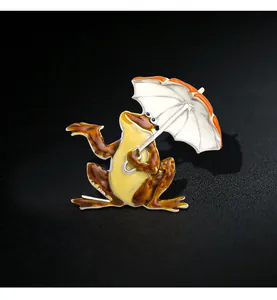 Detailed view of a quirky enamel frog brooch holding an orange and white umbrella.