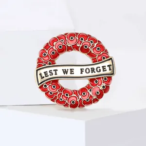 Detailed close-up of a red enamel poppy wreath brooch with a gold Lest We Forget banner