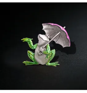 Detailed view of creative frog brooch holding a pink umbrella with vivid enamel texture