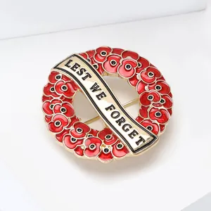 Detail of red enamel poppy wreath brooch with 'Lest We Forget' text banner