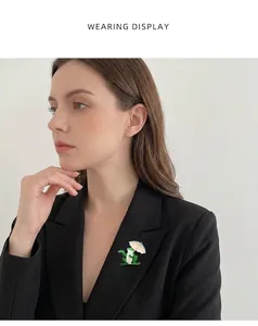 Detailed close-up view of a green enamel frog brooch with umbrella on a black blazer