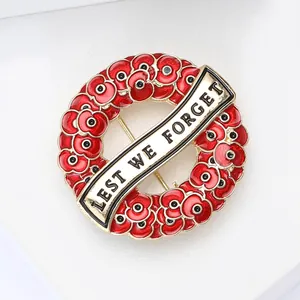Close-up of red enamel poppy wreath brooch with engraved Lest We Forget slogan