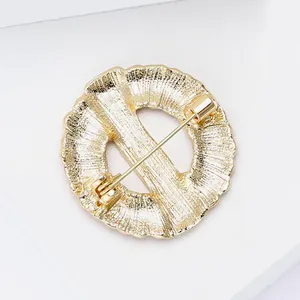 Close-up detail of the golden alloy wreath brooch back showing the pin mechanism.