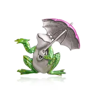 Vintage alloy frog brooch holding a pink umbrella with detailed green enamel finish