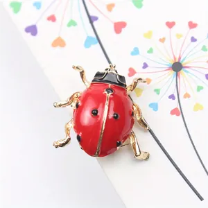 Vue macro détaillée d'une broche coccinelle rouge en alliage doré et émail de qualité