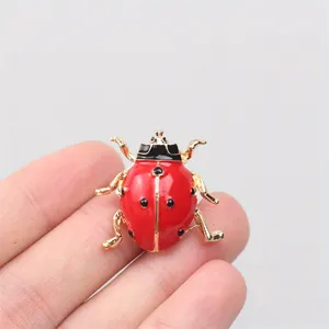 Vue détaillée d'une broche coccinelle rouge avec des pattes en alliage doré