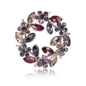 Detailopname van een elegante kransbroche met kleurrijke kristallen bloemblaadjes erop.