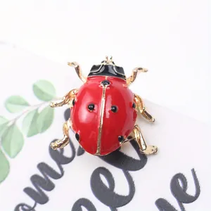 Gros plan détaillé d'une broche insecte coccinelle rouge et dorée avec finition émail