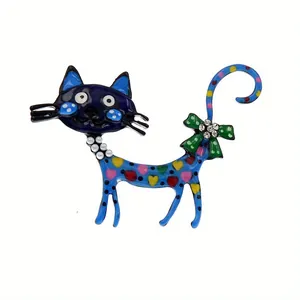 Gedetailleerde close-up van een kleurrijke emaille kattenbroche met blauwe hartjes en strik.