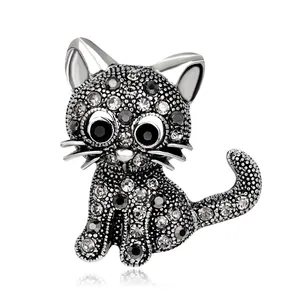 Detailopname van een zilverkleurige kattenbroche bezet met grijze en zwarte kristallen