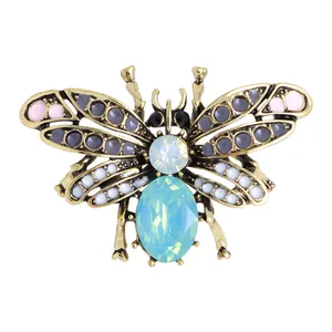 Macro-opname van een gouden bijenbroche met blauw kristal en schitterende steentjes.