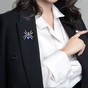 Gedetailleerde weergave van een blauwe kristallen spinnenbroche op een blazer
