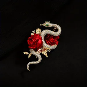 Elegante vintage slangenbroche met rode rozen en groene kristallen ogen op zwarte stof.
