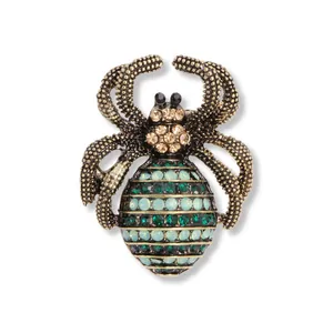 Vintage gouden spinnenbroche met groene en blauwe strass-steentjes op witte achtergrond.