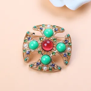 Close-up of vintage Baroque cross brooch with colorful rhinestones and pearls.