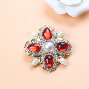 Detailed view of a Baroque brooch with red gems, white pearls and sparkling rhinestones on it